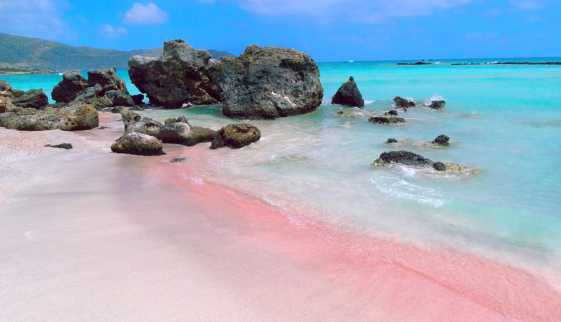 חוף בכרתים עם סלעים שחורים וחול ורוד