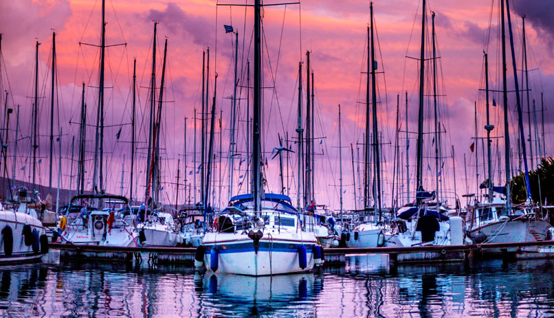 סירות מפרש עוגנות על רקע השקיעה